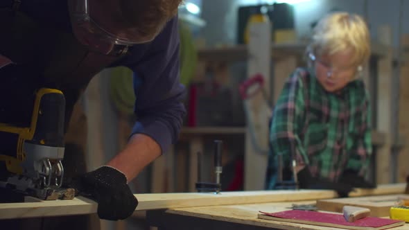 The Boy Helps Dad To Cut a Board. Sliding