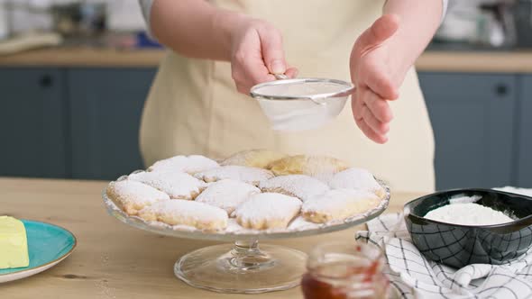 Video of woman sprinkling and decorating cookies with powdered sugar