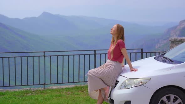 A Young Woman is Relaxing Standing By a Car at a Viewpoint on a Beautiful Canyon of the Cijevna