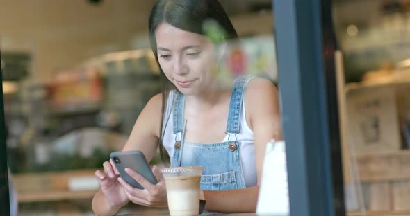 Woman use of mobile phone inside coffee shop