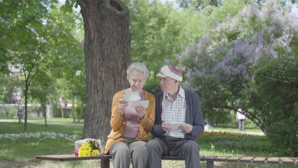 Portrait Cute Adult Couple Looking Old Photos Remembering Happy Moments Sitting on a Bench