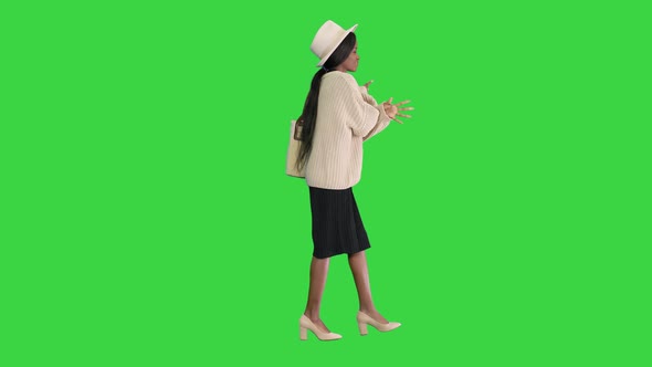 Stylish African American Woman in Knitwear and White Hat Dancing While Walking on a Green Screen