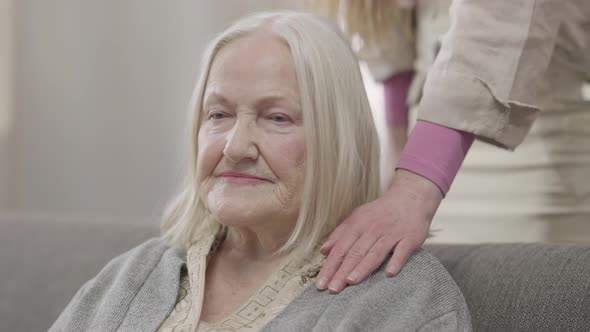 Old Caucasian Woman Sitting at Home As Female Hand Touching Retiree Shoulder