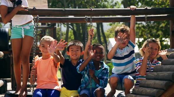 Portrait of happy schoolkids waving hands in playground