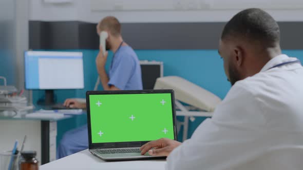 African American Doctor Looking at Mock Up Green Screen Chroma Key Laptop Computer