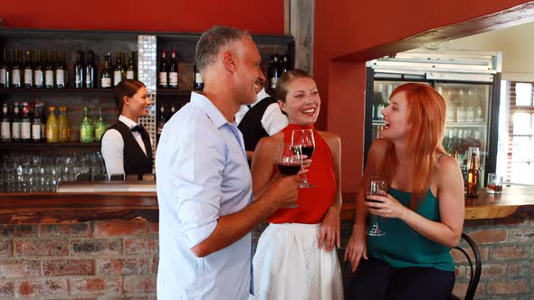 Three friends with wine glass talking to each other at counter