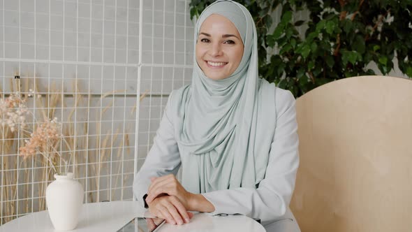 Portrait of Goodlooking Muslim Woman Wearing Traditional Hijab Smiling Indoors in Cafe