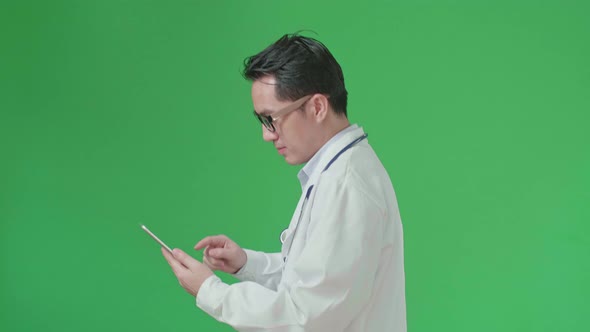 The Side View Of Asian Doctor With Stethoscope Using Tablet While Walking On Green Screen