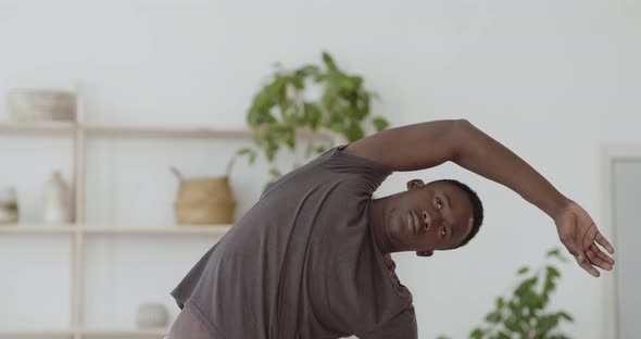 Young African American Guy Training at Home, Tilting To Sides