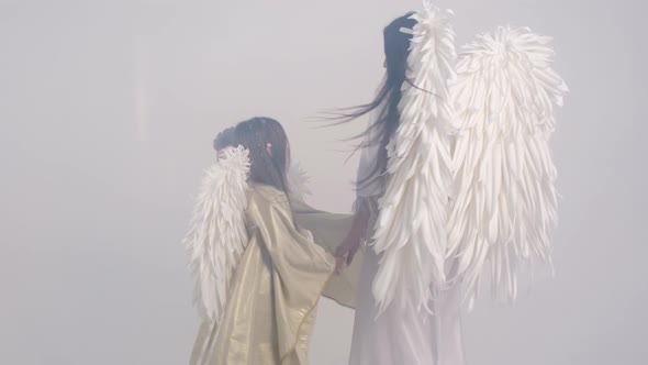 Family Dancing with Angel Wings on a White Background in Smoke