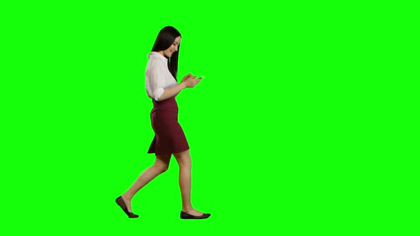 Girl of Asian Appearance Walks the Street, the Phone Looks at Interesting Pictures. Green Screen