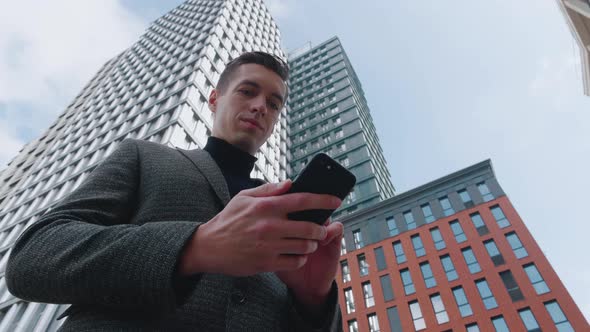 Man Using Business App on Smartphone on City Background. Handsome Young Businessman Communicating on