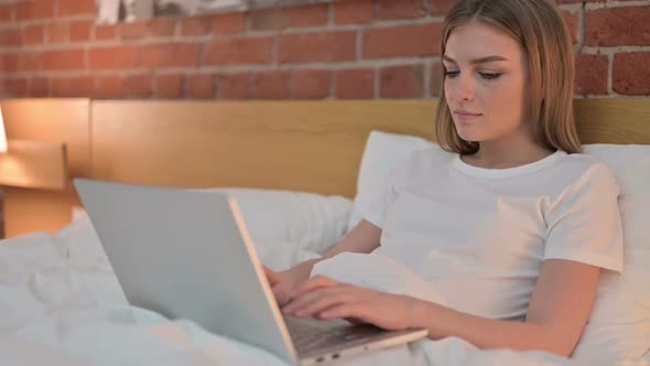 Ambitious Young Female Working on Laptop in Bed