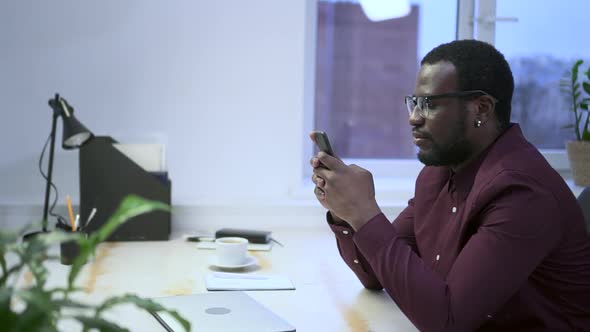 Businessman Using Smartphone and Sitting at Table in Modern Office Spbas