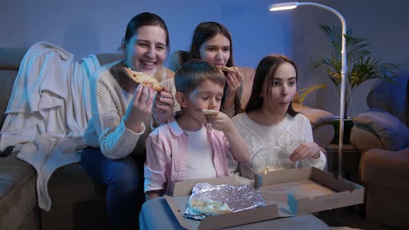 Happy Family Smiling and Laughing While Eating Pizza and Watching TV Movie or Show at Night