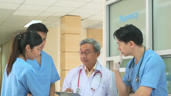 Team of asian doctor nurse consult together on patients file at hospital.