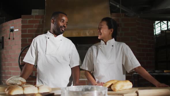Animation of two diverse male and female bakers smiling at camera in bakery
