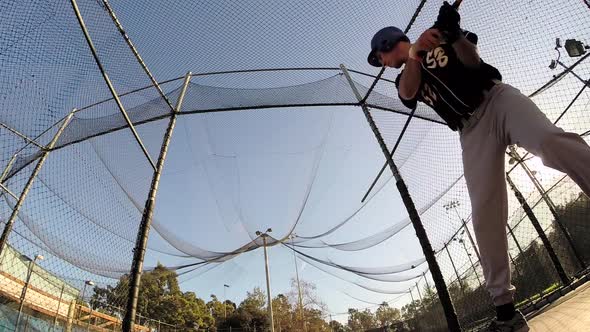 A baseball player practicing at the batting cages.