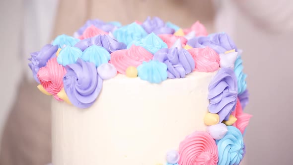 Step by step. Pastry chef piping butter cream frosting on unicorn cake for little girl birthday part