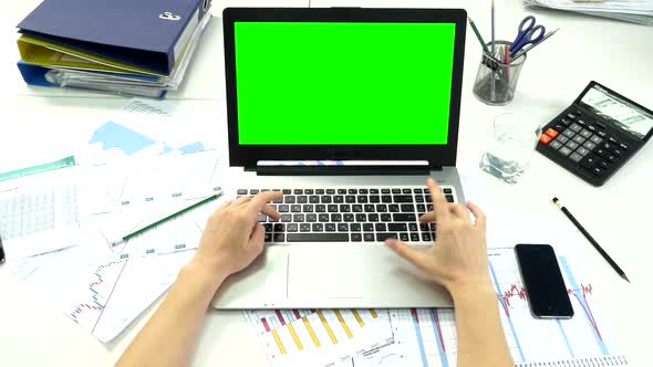 Woman Hand on Laptop Keyboard with Green Screen Monitor in the Office