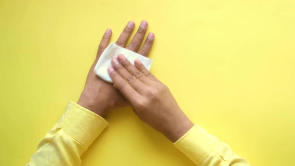 Man Disinfecting His Hands with a Wet Wipe on Yellow Background