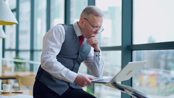 Serious businessman in glasses looking into a laptop