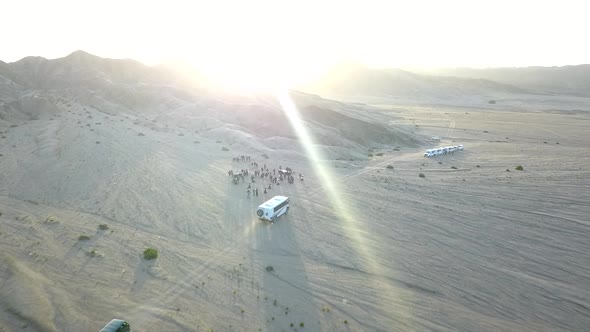 fly-over of buses driving towards a group of people in the Namibian Desert