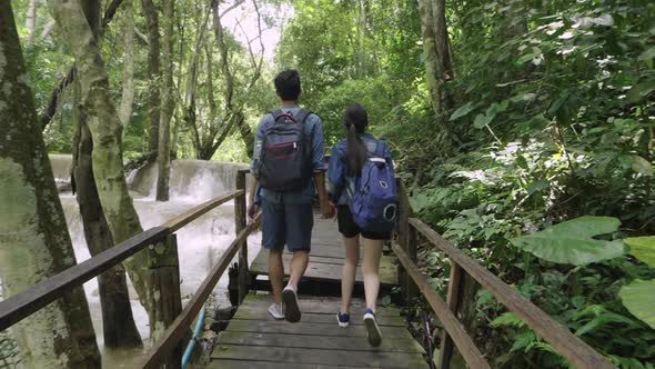 Back View Of Couple Holding Hand Walking Near A Waterfall