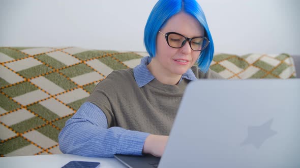 Nerdy girl in glasses working online with laptop computer in 4k stock video clip