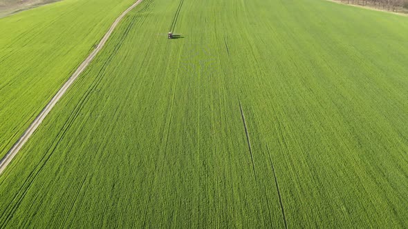 Aerial View of Farming Tractor Spraying on Field with Sprayer