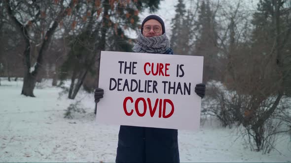 Man Holding a Poster The Cure is Deadlier Than Covid. Anti-vaccination Protest