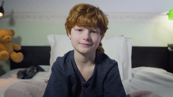 Close-up Portrait of Cute Caucasian Boy with Red Hair and Grey Eyes Looking at Camera and Smiling