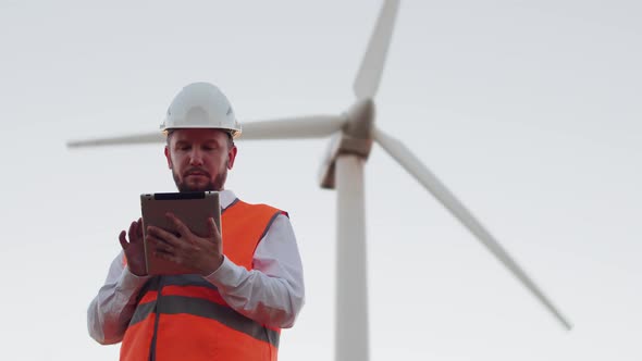 Bottom View of a Portrait of an Engineer with a Beard with a Modern Tablet Looking Into the Camera