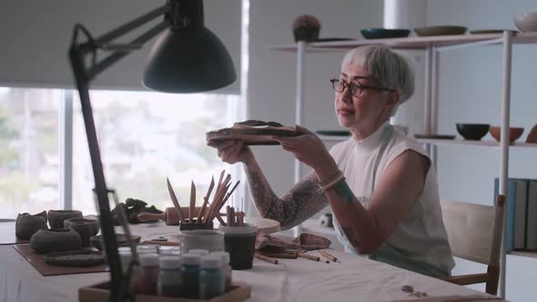 Asian elderly woman enjoying pottery work at home.