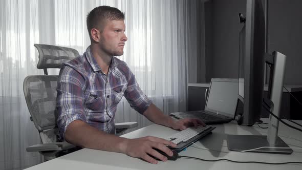 Handsome IT Office Worker Using Two Computers Working on a Project