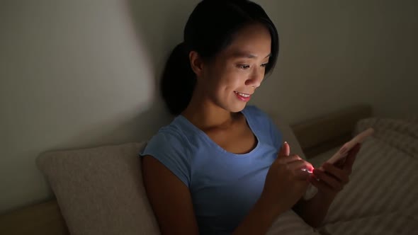 Woman using mobile phone before sleep at night