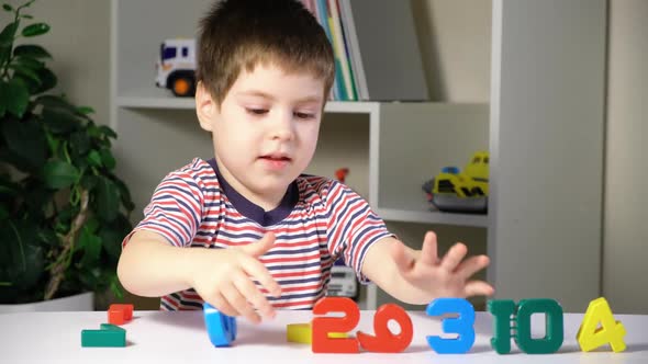 A Preschool Boy Plays with Multicolored Toy Numbers Learns to Count