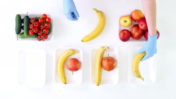 Top View, Volunteer in Protective Gloves Packs Grocery, Puts Fruits and Vegetables in Trays, Close