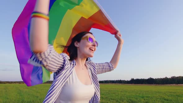 Young Attractive Woman Runs Across Field with LGBT Flag Slow Mo Close Up