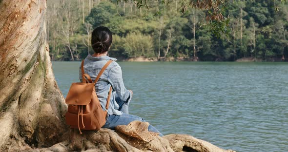 Woman sit on the tree root and enjoy the view