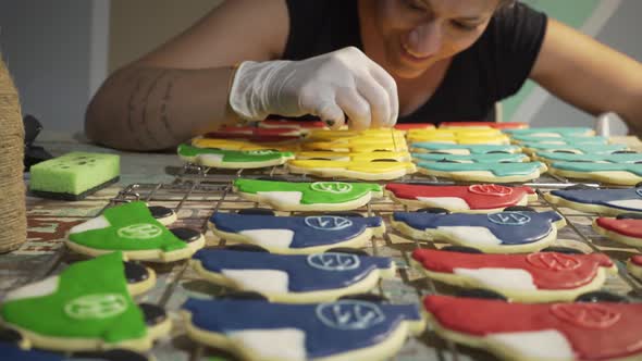 Woman decorates homemade vehicle shaped cookies with sugar icing and smiling. Slide medium shot 4k