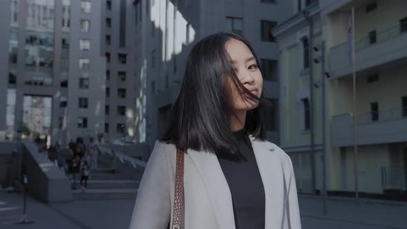 Young Asian Woman Shaking Her Hair and Looking at Camera in the City