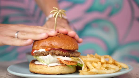 Hands Pressing Buns of a Burger Squeezing Ketchup and Mayo Sauces From It