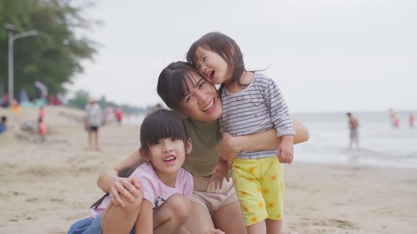 Portrait of Asian happy family mom and kid play sand on beach with sea in background in the evening.