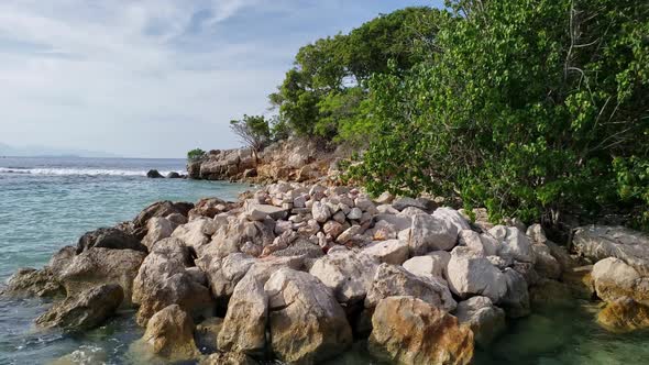 Close up low angle view of clear Caribbean water washing against the rocky shore of a small tropical