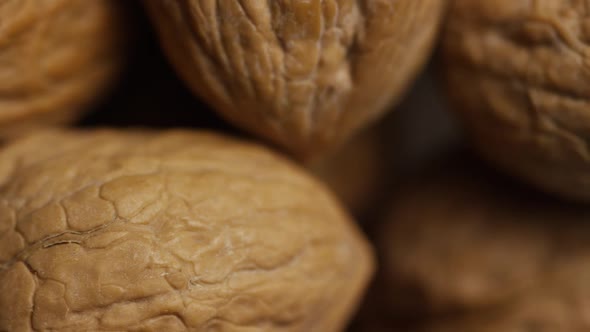 Cinematic, rotating shot of walnuts in their shells on a white surface 