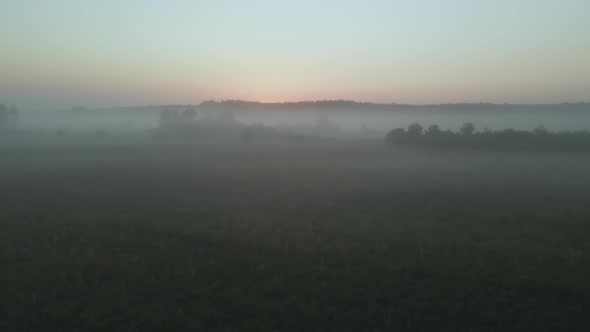 Foggy dawn in the countryside. Foggy river valley and rising sun. Aerial photography.