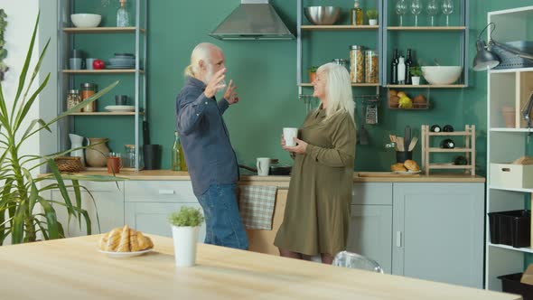 Elderly Couple Relaxing at Home Talking Over a Cup Of Tea in a Cozy Kitchen