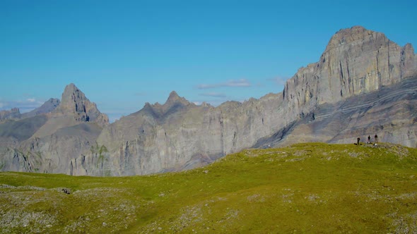 Aerial reveal and orbit around hikers, Grand Muveran massif and the Alps in the background, Switzerl