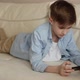 Child Lies on the Couch in His Hands Holding a Phone Plays with It - VideoHive Item for Sale